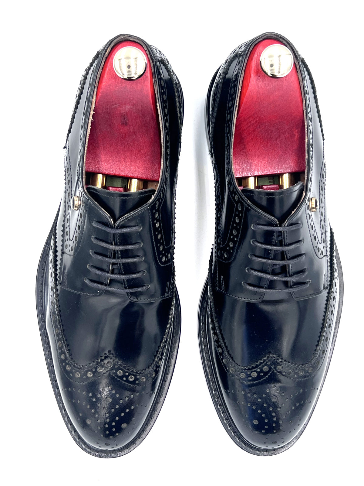 Pair of black dress shoes with red lining on a white background