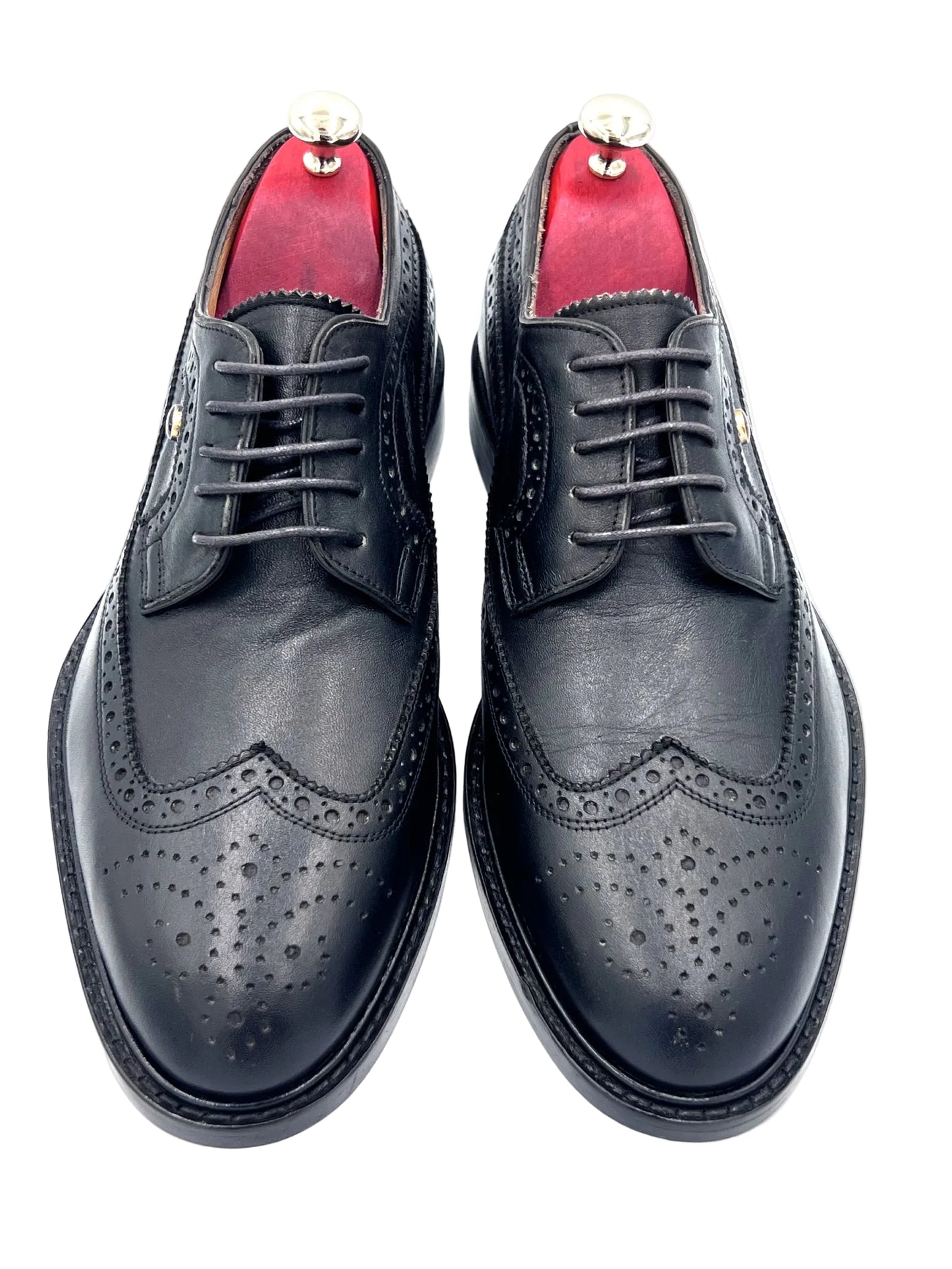 Pair of black leather dress shoes with red lining on a white background