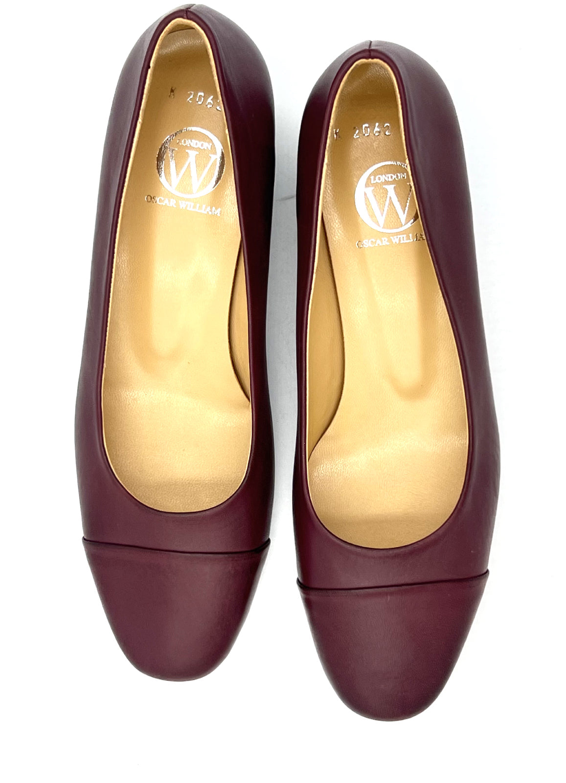 Pair of maroon shoes with gold soles on a white background