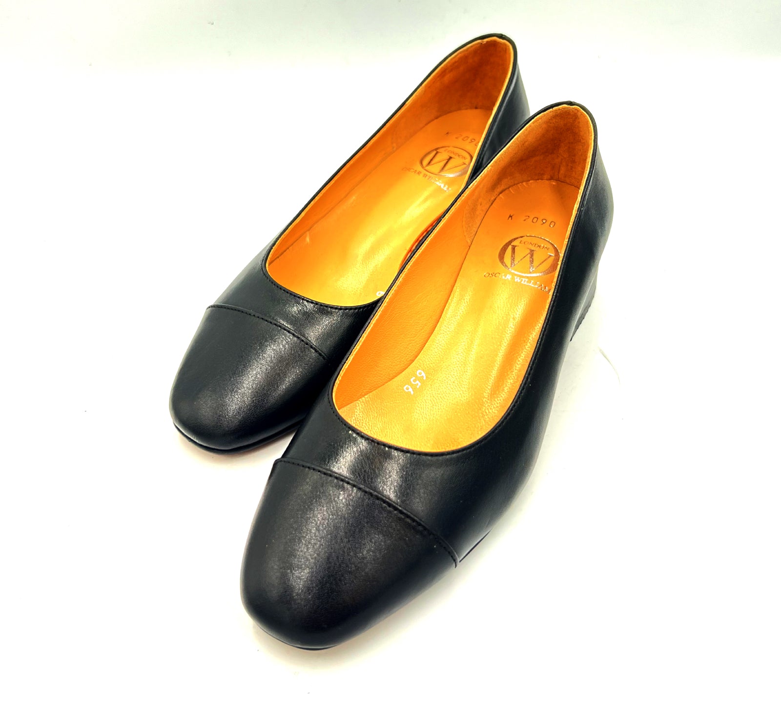 Pair of black leather shoes with orange lining on a white background