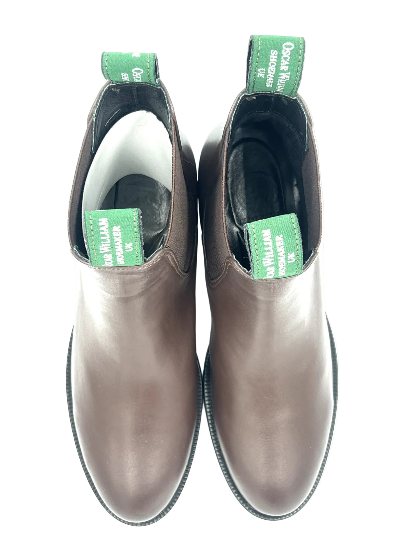 Pair of brown leather boots with green labels on a white background