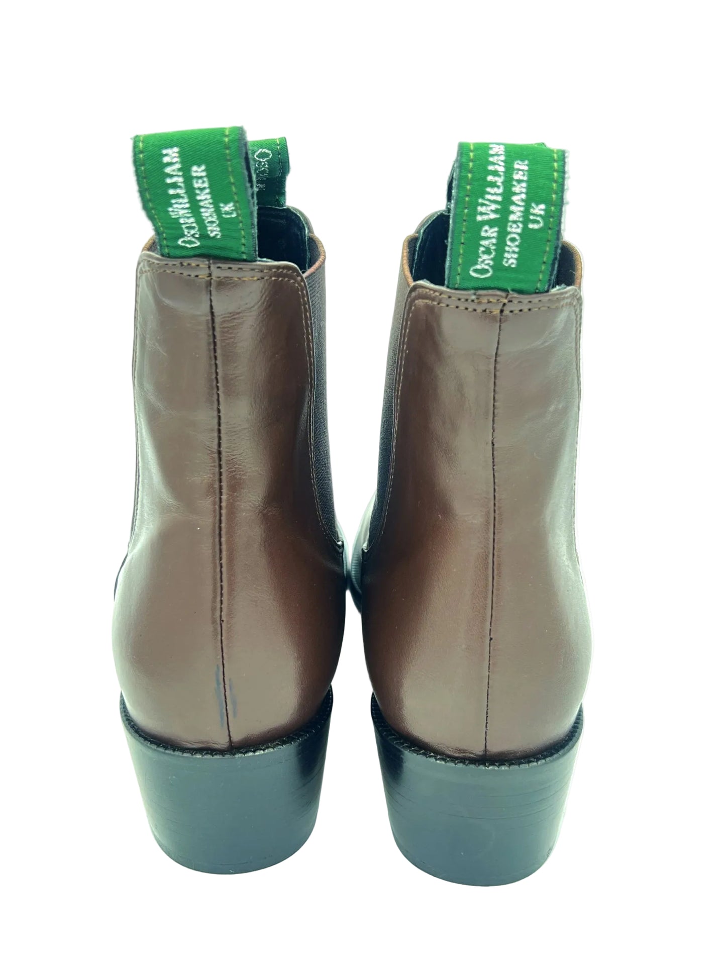 Pair of brown leather boots with green labels on a white background